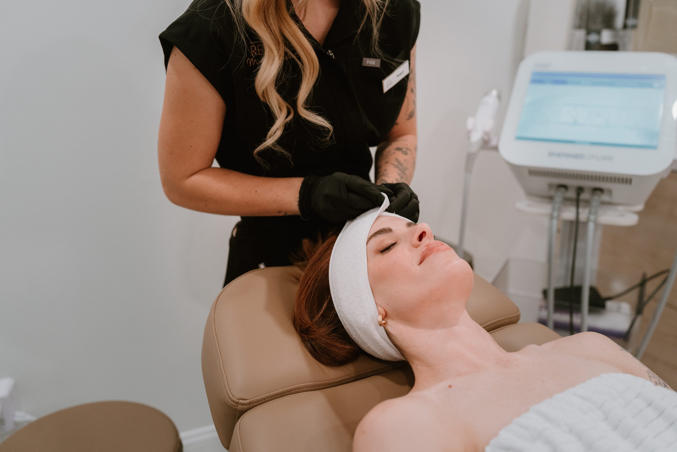 patient at revived medical aesthetics getting a facial done as the staff member is putting a headband on the patient